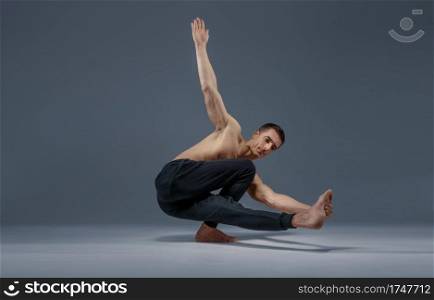 Yoga doing stretching exercise in studio, grey background. Strong man practicing yogi , asana training, top concentration, healthy lifestyle. Yoga doing stretching exercise in studio