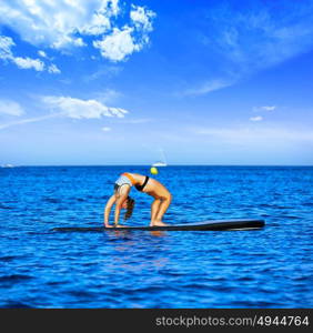 Yoga girl over SUP Stand up Surf board at the ocean sea