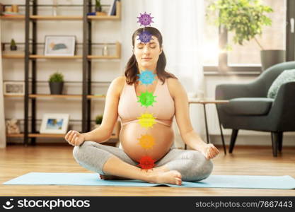 yoga, meditation and mindfulness concept - happy pregnant woman meditating at home with seven chakra symbols. pregnant woman meditating at home