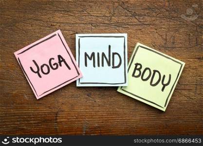 yoga, mind, and body word abstract - handwriting in black ink on sticky notes against rustic wood