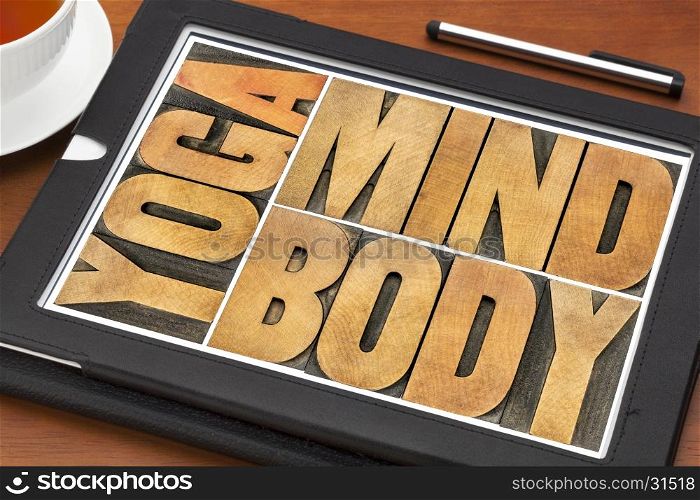 yoga, mind, body word abstract in letterpress wood type printing blocks on a screen of a digital tablet
