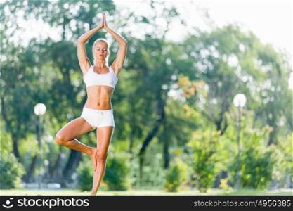 Yoga practice. Young woman in white in summer park practicing yoga
