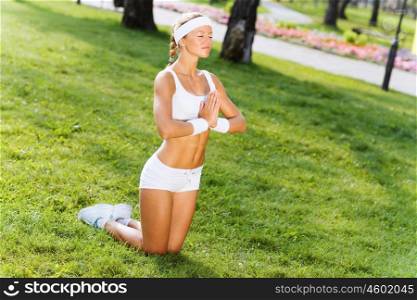 Yoga practice. Young woman in white sitting on grass and practicing yoga