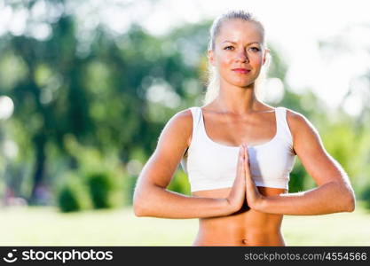 Yoga practice. Young woman in white sitting on grass in lotus pose