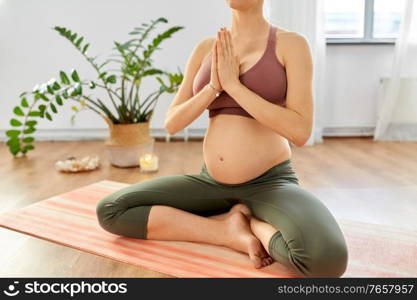 yoga, pregnancy and people concept - pregnant woman meditating at home. pregnant woman doing yoga at home
