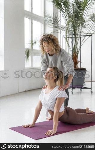 yoga teacher helping woman