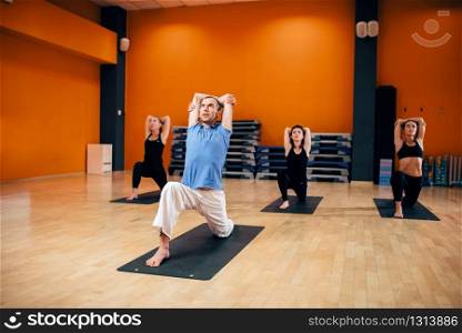 Yoga training class, female group workout with male trainer in gym. Yogi exercise indoor. Yoga training class, female group workout