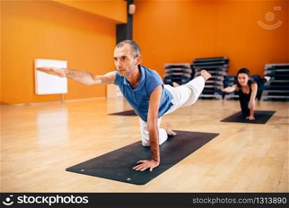 Yoga training, female group with instructor, fat burn exercise, workout in gym. Yogi indoor