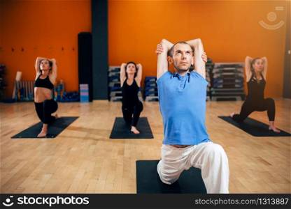 Yoga training, female group with instructor in motion, workout in gym. Yogi exercise indoor