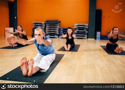 Yoga training, female group with instructor in motion, workout in gym. Yogi exercise indoor. Yoga, female group with instructor in motion