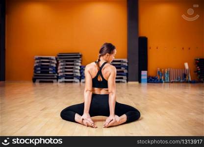 Yoga training, woman in sportswear doing stretching exercise, back view, workout indoor. Yogi class in gym, healthy lifestyle