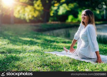 Yoga woman by the water, lord of the fishes, sitting twist pose, green background.. Yoga Woman by the Water, Lord of the Fishes Twist Pose, Green Background.