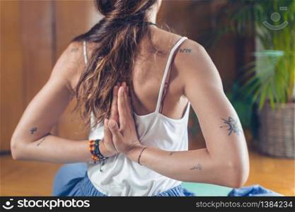 Yoga woman doing reverse prayer pose or penguin pose in studio. Pashchima Namaskarasana or Viparita Namaskarasana