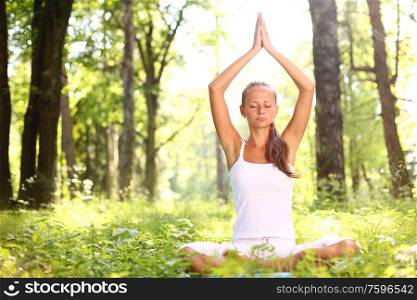 Yoga woman in white on green park grass in lotus asana pose. Yoga woman in park