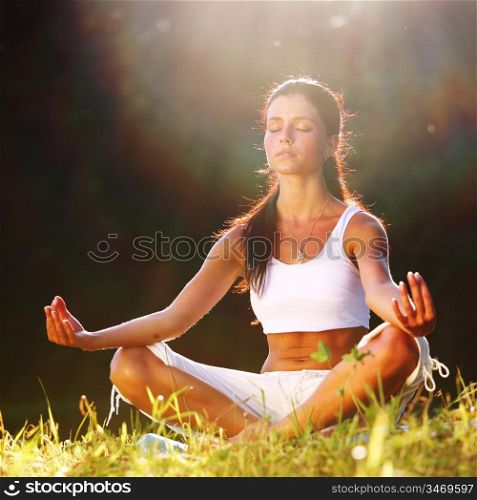 yoga woman on green grass lotus pose in sunrise light