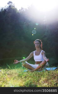 yoga woman on green grass lotus pose in sunrise light