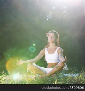yoga woman on green grass lotus pose in sunrise light