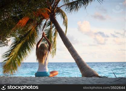 yoga woman on sea coast under palm