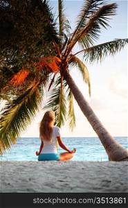yoga woman on sea coast under palm