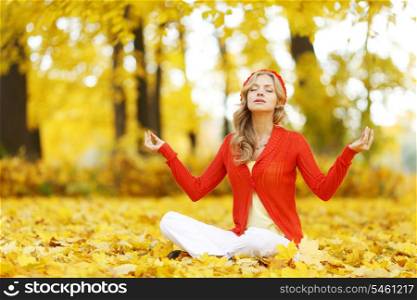 Yoga woman sitting in lotus position in autumn park