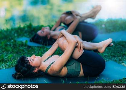 Yoga Women by The Water. Wind Relieving Pose.