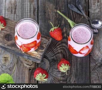 yoghurt with fresh strawberries in a glass jar on wooden table, top view. yoghurt with fresh strawberries in a glass jar