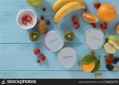 yogurt in a container with tropical fruits on a wooden background, top view. healthy eating concept. dairy products on a blue background
