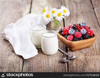 yogurt in a glass jars with fresh berries on wooden table