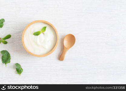 Yogurt in wood bowl on white wooden table Healthy food concept, top view and copy space