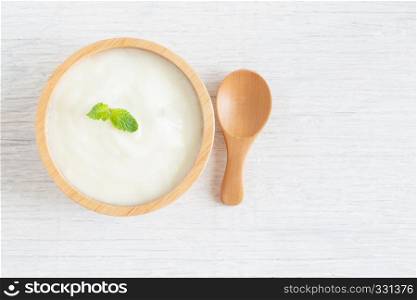 Yogurt in wood bowl on white wooden table Healthy food concept, top view and copy space