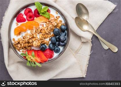 Yogurt with baked granola and berries in small bowl strawberries blueberries. Granola baked with nuts and honey for little sweetness.