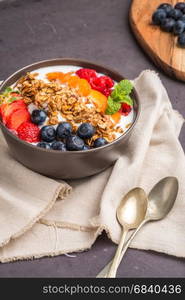 Yogurt with baked granola and berries in small bowl strawberries blueberries. Granola baked with nuts and honey for little sweetness.