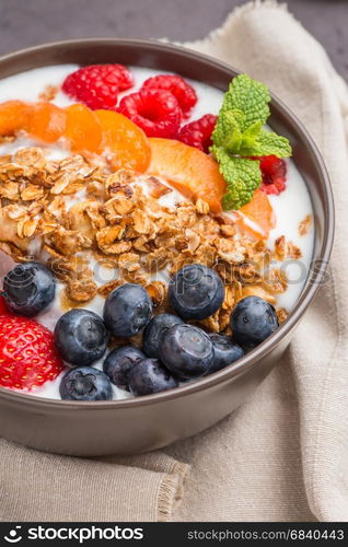 Yogurt with baked granola and berries in small bowl strawberries blueberries. Granola baked with nuts and honey for little sweetness.