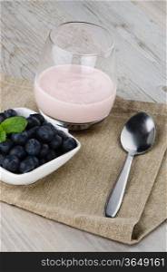 Yogurt with fresh blueberries on a wooden table set.