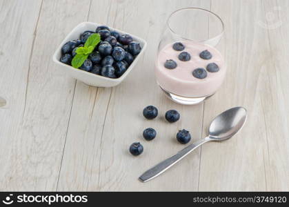 Yogurt with fresh blueberries on a wooden table set.