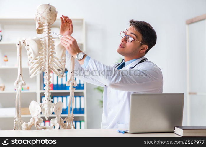 Yong male doctor with skeleton isolated on white