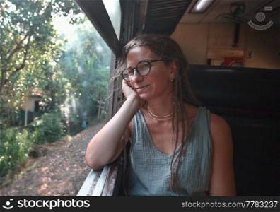 Yong woman  enjoying train ride from Ella to Kandy among tea plantations in the highlands of Sri Lanka