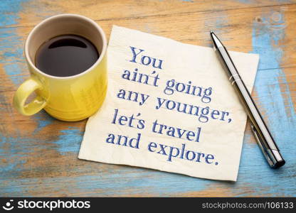 You ain't going any younger, let's travel and explore - handwriting on a napkin with a cup of espresso coffee