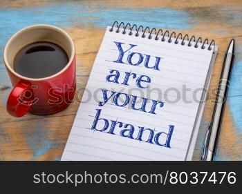 You are your brand - motivation text in spiral notebook with a cup of coffee