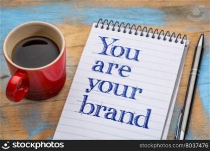 You are your brand - motivation text in spiral notebook with a cup of coffee