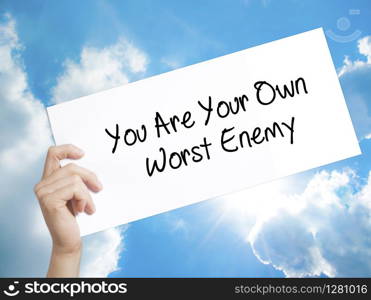 You Are Your Own Worst Enemy Sign on white paper. Man Hand Holding Paper with text. Isolated on sky background. Business concept. Stock Photo