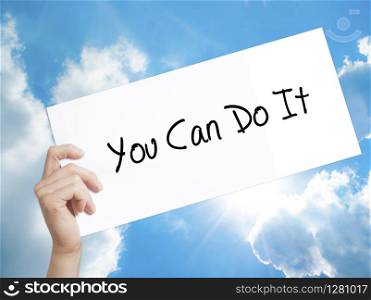 You Can Do It Sign on white paper. Man Hand Holding Paper with text. Isolated on sky background. Business concept. Stock Photo