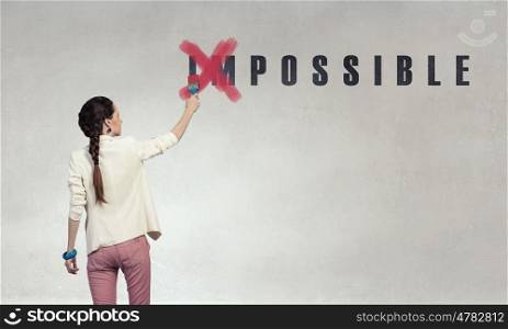 You can make it possible. Young woman crossing letters of word impossible
