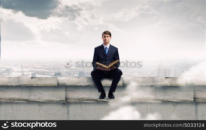 You knowledge is your future!. Handsome businessman sitting on top and reading book