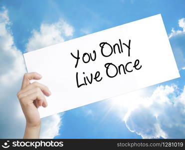 You Only Live Once Sign on white paper. Man Hand Holding Paper with text. Isolated on sky background. Business concept. Stock Photo