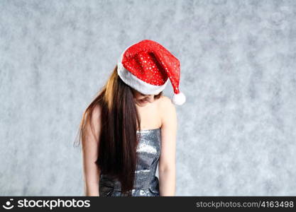 Young 20-25 years sexy Santa in black dress and x-mas hat on grey