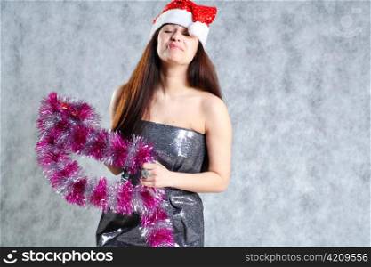 Young 20-25 years sexy Santa in black dress and x-mas hat on grey