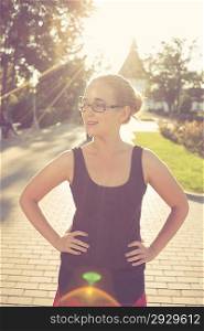 young 20s blond haired women posing outdoors weared black tank top in glasses. Shi is very pretty and fresh looking. Cute romantic girl, attractive blond woman enjoying autumn yellow sunlight.