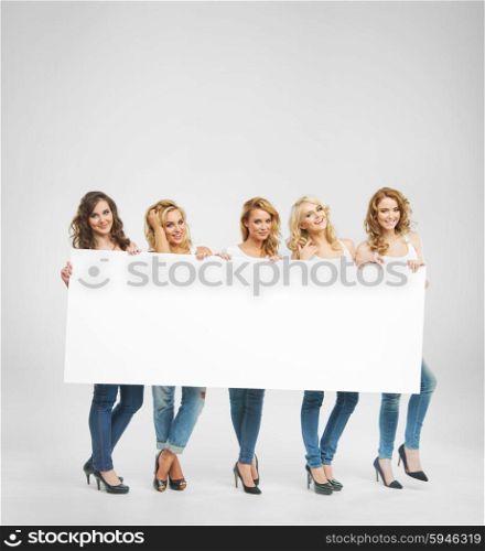 Young adorable girlfriends holding a board
