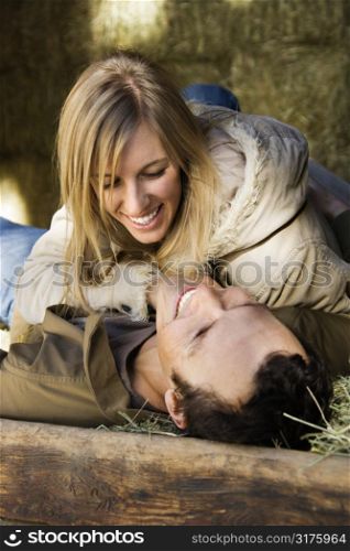 Young adult Caucasian couple lying in hay.